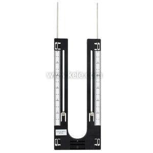 black U‑shaped measuring device with clear tubes and white ruler markings