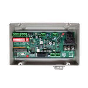 Grey box with a printed circuit board inside featuring DIP switches, green terminal blocks and a conduit hub