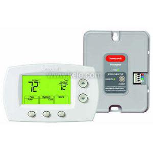A home thermostat set containing a white digital thermostat with a green screen indicating 72 degrees and a separate gray rectangular receiver module featuring a multi-colored wiring connector.