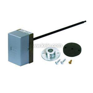 A grey box with a long black rod attached, shown with a round mounting plate, black gasket, and small screws.