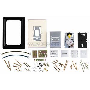Assorted thermostat installation components laid out, including frames, metal plates, small tubing sections and numerous screws and fasteners.