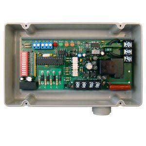 Grey plastic case with internal green circuit board featuring DIP switches, relays and screw terminals.