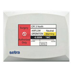 White rectangular wall panel displaying room pressure status with colored screen and text indicators.