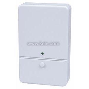 A slim white wall-mounted sensor unit with a small green status light above a round control knob near the bottom