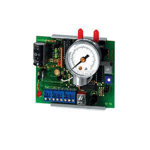 A small green printed circuit board fitted with a round analog gauge and red tubing connectors, surrounded by electronic components and terminal blocks.
