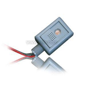 Small grey rectangular sensor module with round lens and vented holes, and three colored wires exiting from the bottom.