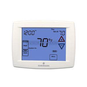 A white rectangular thermostat with a blue backlit screen displaying temperature, time, day, and control icons.
