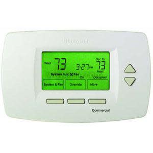 A white rectangular digital thermostat with a green backlit screen displaying the current temperature, set point and time, with arrow and function buttons beneath the display.