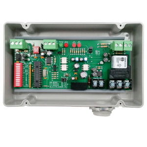 Grey box containing green circuit board with DIP switches, relays and screw terminal blocks.