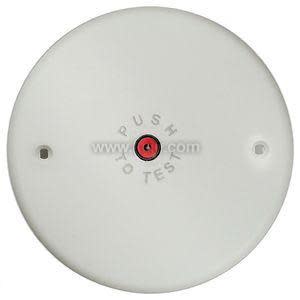Round white device with a central red push button labeled “PUSH TO TEST” and two screw mounting holes.
