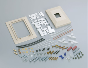Collection of assorted installation hardware including two beige wall plates, metal mounting plates, assorted screws, washers, plastic tubes, connectors and small fittings spread out on a surface.