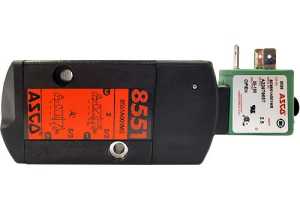 Rectangular black valve body bearing an orange diagram, attached to a small green solenoid coil with two flat prongs and a white label.