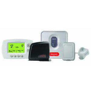 A multi-piece thermostat system including a white programmable thermostat with a green display, a black gateway device, a square gray equipment interface, an extra small rectangular transmitter, and a tethered gray sensor.
