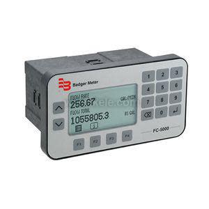 Photograph of a rectangular electronic flow meter labeled 'Badger Meter FC‑5000', featuring an LCD screen showing flow rate readings and a numeric keypad with buttons.