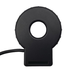 Round black electrical sensor shaped like a donut with a hole in the center, used to measure current, with a small cable extending from one side