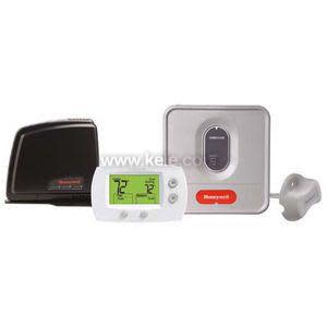 A four-component thermostat kit comprising a black wireless gateway device, a white thermostat with a green display and round buttons, a square gray control module with a red accent, and a small gray sensor with a cord.