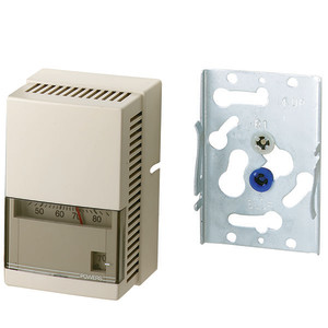 A beige wall thermostat with horizontal vents, an analog temperature scale visible behind a small window, and a separate galvanized mounting bracket