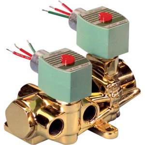 Shiny brass valve assembly with two cube-shaped green solenoids, each topped with a red button, and exposed wire leads.